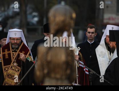 Priester verschiedener christlicher Konfessionen feiern einen Gedenkgottesdienst, während Menschen während der Trauerveranstaltung in Kiew, Ukraine, am 28. November Kerzen anzünden und Blumensträuße aus den Ohren und aus dem arrowwood zum Denkmal der großen Hungeropfer legen. 2020.die Ukraine ehrt das Gedenken an die Opfer der Hungersnöte und der Großen Hungersnot (Holodomor) von 1932 bis 1933, als 4,5 Millionen Ukrainer, darunter 600.000 ungeborene Kinder, vom sowjetischen Regime unter Joseph Stalin verhungert wurden. (Foto von Sergii Chartschenko/NurPhoto) Stockfoto