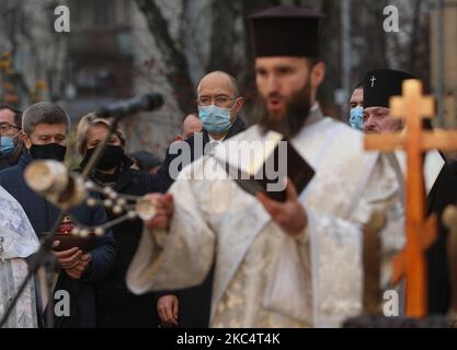 Priester verschiedener christlicher Konfessionen feiern einen Gedenkgottesdienst, während Menschen während der Trauerveranstaltung in Kiew, Ukraine, am 28. November Kerzen anzünden und Blumensträuße aus den Ohren und aus dem arrowwood zum Denkmal der großen Hungeropfer legen. 2020.die Ukraine ehrt das Gedenken an die Opfer der Hungersnöte und der Großen Hungersnot (Holodomor) von 1932 bis 1933, als 4,5 Millionen Ukrainer, darunter 600.000 ungeborene Kinder, vom sowjetischen Regime unter Joseph Stalin verhungert wurden. (Foto von Sergii Chartschenko/NurPhoto) Stockfoto