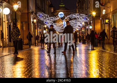 Passanten in schützenden Gesichtsmasken werden an einem kalten Winterabend in der Florianska Straße am Hauptmarkt in der Krakauer Altstadt gesehen, als die Stadt unter teilweiser Coronavirus-Sperre neue Weihnachtslichter aufstellte, Krakau, Polen, 29. November 2020. Die Altstadt von Krakau ist in der Regel sehr voll mit Touristen, jetzt bleibt es weitgehend verlassen wegen Covid-19 Einschränkungen. (Foto von Dominika Zarzycka/NurPhoto) Stockfoto