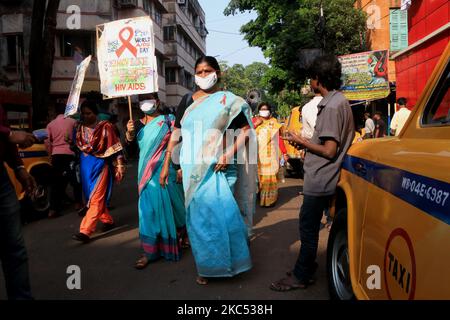 Indische Aktivisten, die gegen eine schützende Gesichtsmask ankriegen, halten ein Plakat bereit - gehen Sie an einer Kundgebung anlässlich des Welt-Aids-Tages in Kalkutta, Indien, Dienstag, den 1. Dezember 2020. Auf den Plakaten steht: „Von AIDS fernhalten, nicht von den Patienten“, links: „An einen einzelnen Partner halten. Verwenden Sie Kondome, „zentrieren“, „Verwenden Sie keine Spritzen, Nadeln, Klingen oder Rasiermesser, die von anderen verwendet werden“, richtig. (Foto von Debajyoti Chakraborty/NurPhoto) Stockfoto