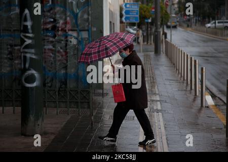 Eine Frau hängt einen Regenschirm, um sich vor dem Regen zu schützen, gleichzeitig trägt sie eine Maske als Vorsichtsmaßnahme gegen covid19. (Foto von Konstantinos Zilos/NurPhoto) Stockfoto