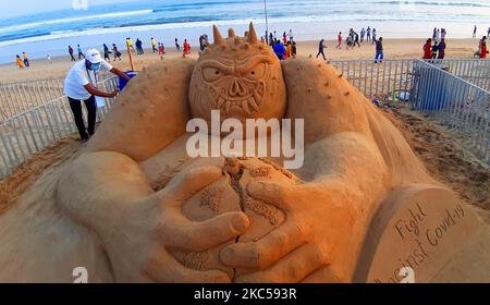 Der indische Sandkünstler Ajay Rawat gibt seiner Skulptur auf der Covid-19 während des Internationalen Sand Art Festivals am Chandrabhaga Strand, Konark, Puri, Odisha, Indien am 05. Dezember 2020 einen letzten Schliff. Das berühmte Konark Festival, das Sandkunstfestival, wird am Chandrabhaga Beach organisiert, der etwa einen Kilometer vom Weltkulturerbe Konark entfernt ist. (Foto von Himanshu Sharma/NurPhoto) Stockfoto