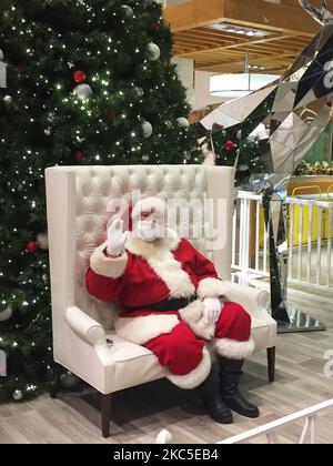 Mann, der als Weihnachtsmann gekleidet ist und eine Gesichtsmaske trägt, um ihn vor dem neuartigen Coronavirus (COVID-19) zu schützen, als er während der Weihnachtszeit in Vaughan, Ontario, Kanada, am 07. Dezember 2020 in einem Einkaufszentrum auf Kinder wartet, die mit ihm ein Foto machen. (Foto von Creative Touch Imaging Ltd./NurPhoto) Stockfoto