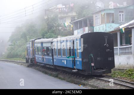 Der kleine Zug fährt neben den Häusern vorbei. Die Darjeeling Himalayan Railway oder DHR oder bekannt als Toy Train wegen der engen 2ft Gauge auf den Hängen des Himalaya in Indien. Der Zug verkehrt zwischen New Jalpaiguri und Darjeeling in Westbengalen, erbaut 1881 und erreicht eine Höhe von 2200m. Über dem Meeresspiegel. Die Lokomotive verwendet Diesel, aber auch Dampflokomotiven der B-Klasse kommen zum Einsatz und pendeln Einheimische und Touristen von Ghum nach Darjeeling auf einer Strecke mit Panoramablick auf die Berge, die Pisten, die Teeplantage und den Pass von den Städten neben den Häusern und Märkten. Seit 1999 UNESCO dez Stockfoto