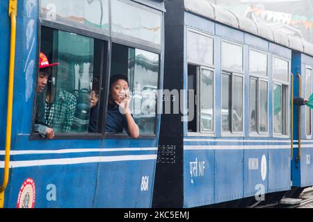 Kinder aus der Sicht der offenen Fenster des Zuges. Die Darjeeling Himalayan Railway oder DHR oder bekannt als Toy Train wegen der engen 2ft Gauge auf den Hängen des Himalaya in Indien. Der Zug verkehrt zwischen New Jalpaiguri und Darjeeling in Westbengalen, erbaut 1881 und erreicht eine Höhe von 2200m. Über dem Meeresspiegel. Die Lokomotive verwendet Diesel, aber auch Dampflokomotiven der B-Klasse kommen zum Einsatz und pendeln Einheimische und Touristen von Ghum nach Darjeeling auf einer Strecke mit Panoramablick auf die Berge, die Pisten, die Teeplantage und den Pass von den Städten neben den Häusern und Märkten. Seit 1999 Stockfoto