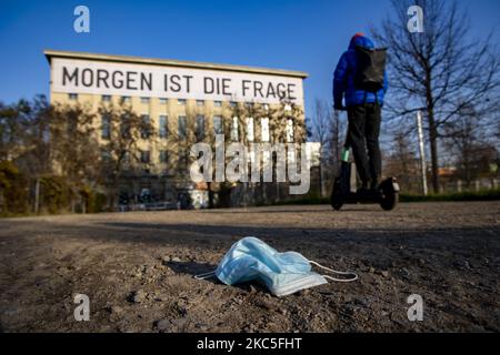 Am 8. Dezember 2020 liegt eine medizinische Maske auf dem Weg zum Eingang des Techno-Clubs Berghain in Berlin. An der Fassade des Gebäudes hängt ein Banner, Kunstwerk des Künstlers Rirkrit Tiravanija, mit der Aufschrift "Morgen ist die Frage". Deutschland, wenn es vor einer Weihnachtssaison mit restriktiven Regeln steht, die private Versammlungen, Handel, Bewegung usw. einschränken, sich von den Bundes- und Kommunalbehörden dazu entschlossen hat, auf die zweite Welle der Coronavirus-Pandemie zu reagieren, da die Anzahl der Fälle nach mehr als einem Monat teilweiser Sperrung, Nimmt ab, aber weit von der gewünschten Schwelle von 50 Fällen für 100,00 Stockfoto