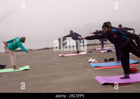 Eine Gruppe von Menschen führt an einem kalten Wintermorgen in Narayanganj, Bangladesch, am Ufer des Flusses unter starkem Nebel Yoga durch. Am 9,2020. Dezember (Foto: Mushfiqul Alam/NurPhoto) Stockfoto