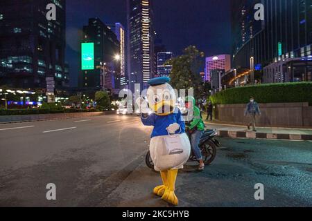 Ein Mann, der während des regnerischen Tages am 10. Dezember 2020 im Central Business District in Jakarta als Donald Duck gekleidet war. Präsident Joko Widodo räumte ein, dass Indonesiens COVID-19-Todesrate die durchschnittliche Todesfallrate (CFR) für das Coronavirus überschritten habe, da der aktuelle CFR des Landes bei 3,1 Prozent liegt und damit über dem globalen Durchschnitt von 2,32 Prozent liegt. Der Präsident hat den Regionalverwaltungen mit einer ernsten Warnung gedroht, wenn der Anstieg der Infektionen unvermindert anhält, insbesondere in Regionen, in denen die täglichen Fälle kontinuierlich zunehmen. Nach Angaben von Statistics Indonesia (BPS), Indones Stockfoto