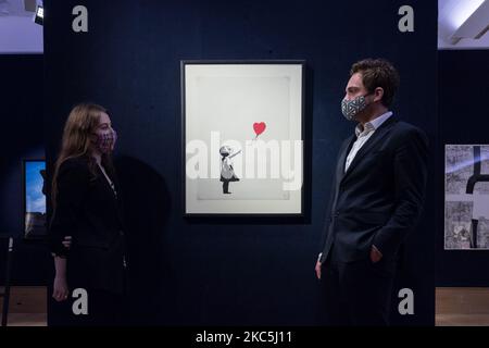 (NUR ZUR REDAKTIONELLEN VERWENDUNG) Mitarbeiter posieren mit Banksy's (geboren 1975) Girl with Balloon, 2004 (est. £120.000 - 180.000) während eines Fotoaufrufs für Bonhams' Prints & Multiples Sale am 10. Dezember 2020 in London, England. (Foto von Wiktor Szymanowicz/NurPhoto) Stockfoto