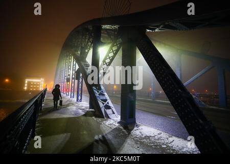 Eine Frau geht am 11. Dezember 2020 an einem nebligen Winterabend in Krakau, Polen, über eine Brücke. (Foto von Beata Zawrzel/NurPhoto) Stockfoto