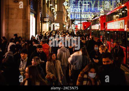 Einkäufer, die zum Teil Gesichtsmasken tragen, gehen am 12. Dezember 2020 unter Weihnachtsschmuck in der geschäftigen Oxford Street in London, England, spazieren. Die Spekulationen, dass London unter die „Tier 3“-Einschränkungen des Coronavirus fallen könnte, haben diese Woche zugenommen, angesichts steigender Zahlen von Menschen, die in der Stadt positiv auf Covid-19 getestet wurden. Im Rahmen von Tier 3 würde das Gastgewerbe nur wenige Wochen nach der Wiedereröffnung am Ende der zweiten nationalen Sperre am 2. Dezember wieder schließen müssen, außer als Imbiss zu agieren. Die Entscheidung soll am kommenden Mittwoch auf einer Sitzung getroffen werden, die angeblich von der Leitung von „Bbrücke“ geleitet werden soll Stockfoto