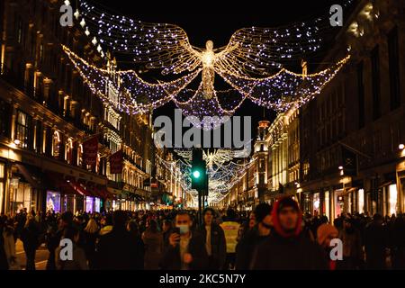 Einkäufer, die teilweise Gesichtsmasken tragen, gehen am 12. Dezember 2020 in der geschäftigen Regent Street in London, England, unter Weihnachtsschmuck. Die Spekulationen, dass London unter die „Tier 3“-Einschränkungen des Coronavirus fallen könnte, haben diese Woche zugenommen, angesichts steigender Zahlen von Menschen, die in der Stadt positiv auf Covid-19 getestet wurden. Im Rahmen von Tier 3 würde das Gastgewerbe nur wenige Wochen nach der Wiedereröffnung am Ende der zweiten nationalen Sperre am 2. Dezember wieder schließen müssen, außer als Imbiss zu agieren. Die Entscheidung soll am kommenden Mittwoch auf einer Sitzung getroffen werden, die angeblich von der Leitung von „Bbrücke“ geleitet werden soll Stockfoto