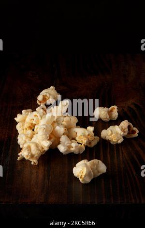 Popcornstapel auf dunklem rustikalem Holztisch und schwarzem Hintergrund Stockfoto