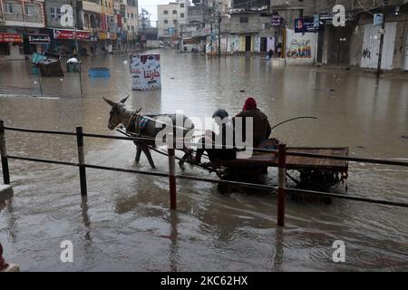 Am 17. Dezember 2020 werden Palästinenser in überschwemmten Straßen während heftiger Regenfälle im Lager Jabalia im nördlichen Gazastreifen gesehen. (Foto von Majdi Fathi/NurPhoto) Stockfoto