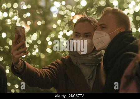 Menschen in Schutzmasken machen am 20. Dezember 2020 Selfies am Weihnachtsbaum im Zentrum von St. Petersburg, Russland. Die Zahl der Fälle von Coronavirus in St. Petersburg überstieg 140 Tausend Menschen (Foto: Valya Egorshin/NurPhoto) Stockfoto