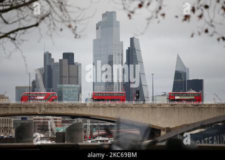 Busse überqueren die Waterloo Bridge am 21. Dezember 2020 an den Türmen des Finanzviertels der City of London in London, England. London verbrachte heute seinen zweiten Tag, der möglicherweise Monate unter den neu eingeführten „Tier 4“-Coronavirus-Beschränkungen sein könnte. Nach den Regeln der Stufe 4 müssen nicht unbedingt erforderliche Geschäfte und viele andere Unternehmen, einschließlich Fitnessstudios und Friseure, schließen, wobei die Leute angewiesen werden, sich außerhalb von ausgenommenen Umständen wie Reisen zur Arbeit oder zur Ausbildung zu Hause zu halten. Auch das Vermischen in Innenräumen zwischen Menschen in verschiedenen Haushalten ist im Rahmen der neuen Stufe verboten, was die Weihnachtspläne für einen großen Teil der aufwirft Stockfoto