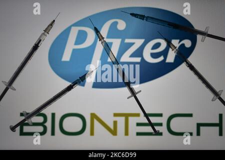 Ein illustratives Foto mit medizinischen Spritzen, die vor dem Pfizer-BioNTech-Logo auf Bildschirmen im Hintergrund am Heiligabend zu sehen sind. Am Donnerstag, den 24. Dezember 2020, in Dublin, Irland. (Foto-Illustration von Artur Widak/NurPhoto) Stockfoto