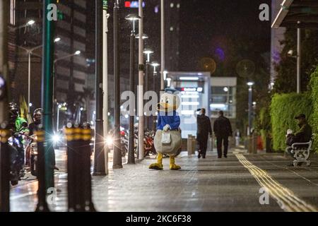 Ein Mann, der während des regnerischen Tages am 24. Dezember 2020 im Central Business District in Jakarta als Donald Duck gekleidet war. Jeden Abend trägt Jimmy Wuri ein Donald Duck Kostüm, um die Menschen auf der Straße zu unterhalten. Jimmy wurde aufgrund der Pandemie im Juli von einem Export- und Importunternehmen entlassen. Unter Verwendung der verbleibenden Abfindungszahlung kaufte Jimmy ein Donald Duck Kostüm für 1.500.000 IDR (106 USD). Er lief 15 Kilometer und spielte lustig, um die Leute zu unterhalten, er bat nie um Geld. An einem Tag erhält Jimmy 100.000 IDR (7 USD) von Menschen, die von seinen Handlungen unterhalten werden. Das Geld wird verwendet, um eine Miete für Hou zu zahlen Stockfoto