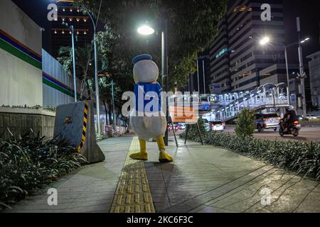 Ein Mann, der am 24. Dezember 2020 im Central Business District in Jakarta als Donald Duck gekleidet war. Jeden Abend trägt Jimmy Wuri ein Donald Duck Kostüm, um die Menschen auf der Straße zu unterhalten. Jimmy wurde aufgrund der Pandemie im Juli von einem Export- und Importunternehmen entlassen. Unter Verwendung der verbleibenden Abfindungszahlung kaufte Jimmy ein Donald Duck Kostüm für 1.500.000 IDR (106 USD). Er lief 15 Kilometer und spielte lustig, um die Leute zu unterhalten, er bat nie um Geld. An einem Tag erhält Jimmy 100.000 IDR (7 USD) von Menschen, die von seinen Handlungen unterhalten werden. Das Geld wird verwendet, um eine Miete für Häuser in einem Slum zu zahlen Stockfoto