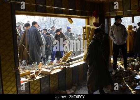 Menschen in Kashmiri beurteilen das beschädigte Wohnhaus im Dorf Kanigam im Bezirk Shopian, südlich von Srinagar, im indischen Kaschmir, am 26. Dezember 2020. Bei einem nächtlichen Treffen wurden zwei lokale kashmiritische Millitanten getötet und zwei indische paramilitärische Truppen verletzt. (Foto von Muzamil Mattoo/NurPhoto) Stockfoto