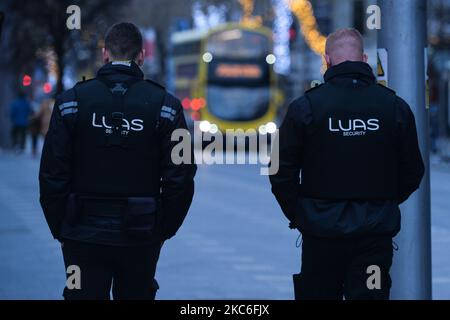 Zwei LUAS-Sicherheitsagenten wurden am St. Stephen's Day am O'Connell Steet im Stadtzentrum von Dublin gesehen. Taoiseach Micheal Martin kündigte am 22.. Dezember eine Reihe neuer Level-5-Beschränkungen an, die die Ausbreitung des Coronavirus eindämmen sollen. Dazu gehören Beschränkungen der Personenbesatzung und die Öffnung aller nicht unbedingt notwendigen Einzelhandelsgeschäfte (Geschäfte können zwar geöffnet bleiben, müssen aber die Umsätze im Januar verschieben). Das Gesundheitsministerium meldete heute einen neuen täglichen Rekord von neuen Fällen für die Republik Irland mit 1.296 neuen Fällen und 6 Todesfällen (2.294 neue Fälle und 26 bestätigte Todesfälle auf der Insel Irland). Stockfoto