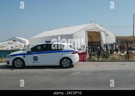 Ein Polizeifahrzeug außerhalb des neuen temporären Flüchtlingslagers in Kara Tepe - Mavrovouni mit großen weißen Zelten mit dem UNHCR- oder UNICEF-Logo und Asylbewerbern, die Schlange stehen, um sich anzumelden und Vorräte wie Nahrung, Betten, Kleidung usw. vom Haupteingang aus zu sehen. Das neue eingezäunte Lager ist ein ehemaliges Militärgebiet, Schießplatz der Hellenischen Armee, in der Nähe der Stadt Mytilene auf der Insel Lesbos in Griechenland. Das neue Lager wurde nach dem Brand vom 9. September 2020 gegründet, als eines der größten Flüchtlingslager Europas, das Moria-Flüchtlingslager (Aufnahme-, Identifikations- und Registrierungszentrum), verbrannt wurde. Al Stockfoto