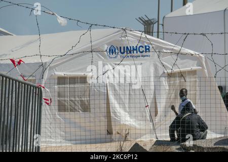 Neues provisorisches Flüchtlingslager in Kara Tepe - Mavrovouni mit großen weißen Zelten mit dem UNHCR- oder UNICEF-Logo und Asylbewerbern, die auf die Registrierung warten und Vorräte wie Nahrung, Betten, Kleidung usw. vom Haupteingang aus gesehen haben. Das neue eingezäunte Lager ist ein ehemaliges Militärgebiet, Schießplatz der Hellenischen Armee, in der Nähe der Stadt Mytilene auf der Insel Lesbos in Griechenland. Das neue Lager wurde nach dem Brand vom 9. September 2020 gegründet, als eines der größten Flüchtlingslager Europas, das Moria-Flüchtlingslager (Aufnahme-, Identifikations- und Registrierungszentrum), verbrannt wurde. Alle Bewohner, die Asyl suchen Stockfoto