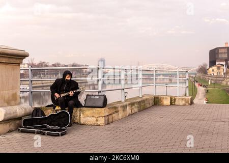 Ein Mann in einer schützenden Gesichtsmaske wird gesehen, wie er an der Weichsel im Bezirk Podgorze in Krakau Gitarre spielt, als die polnische Regierung eine schwere Coronavirus-Sperre einführte - Krakau, Polen, 3. Januar 2021. (Foto von Dominika Zarzycka/NurPhoto) Stockfoto