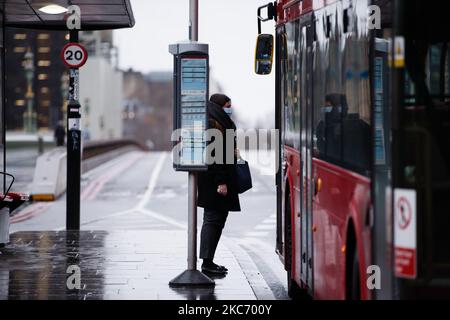 Eine Frau mit Gesichtsmaske wartet am 5. Januar 2021 darauf, an Bord eines Busses auf der Westminster Bridge Road in London, England, zu gehen. England begann heute seine dritte nationale Sperre, wobei die Menschen im ganzen Land erneut angewiesen wurden, außer für spezielle Ausnahmen zu Hause zu bleiben, wobei die Schulen wieder geschlossen wurden, wie sie es bei der ersten Sperre im vergangenen Frühjahr taten. Die Verhängung dieser neuen Beschränkungen, die gestern Abend in einer Fernsehansprache des britischen Premierministers Boris Johnson angekündigt wurde, ist eine Reaktion auf die Befürchtung der Behörden, dass der National Health Service (NHS) bald mit Covid-19 überfordert werden könnte Stockfoto