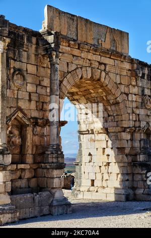 Die Ruinen des Arch of Caracalla (216-217 n. Chr.) in der antiken römischen Stadt Volubilis in Meknes, Marokko, Afrika. Volubilis ist eine teilweise ausgegrabene römische Stadt, die im 3.. Jahrhundert v. Chr. als phönizische (und später karthagische) Siedlung erbaut wurde. Die Stätte wurde ausgegraben und enthüllte viele feine Mosaiken, darunter einige der prominenteren öffentlichen Gebäude und hochwertige Häuser wurden restauriert oder rekonstruiert. Heute ist es ein UNESCO-Weltkulturerbe, das als „außergewöhnlich gut erhaltenes Beispiel einer großen römischen Kolonialstadt am Rande des Imperium“ aufgeführt wird. (Foto von Creative Touch I Stockfoto