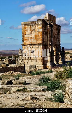 Die Ruinen des Caracalla-Bogens (216-217 n. Chr.) in der antiken römischen Stadt Volubilis in Meknes, Marokko, Afrika. Volubilis ist eine teilweise ausgegrabene römische Stadt, die im 3.. Jahrhundert v. Chr. als phönizische (und später karthagische) Siedlung erbaut wurde. Die Stätte wurde ausgegraben und enthüllte viele feine Mosaiken, darunter einige der prominenteren öffentlichen Gebäude und hochwertige Häuser wurden restauriert oder rekonstruiert. Heute ist es ein UNESCO-Weltkulturerbe, das als „außergewöhnlich gut erhaltenes Beispiel einer großen römischen Kolonialstadt am Rande des Imperium“ aufgeführt wird. (Foto von Creative Touch I Stockfoto