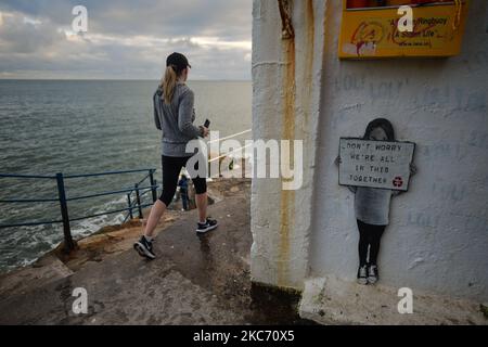 Eine Frau kommt an einem Tierheim vorbei, in dem Kunstwerke mit der Aufschrift „ Don't Worry We're All in This Together“ zu sehen sind, die während der COVID-19-Sperre auf Ebene 5 am Vico-Badeort Hawk Cliff in Dalkey zu sehen waren. Das Gesundheitsministerium meldete heute 5.325 neue Covid-19-Fälle und 17 Todesfälle. Am Dienstag, den 5. Januar 2021, in Dublin, Irland. (Foto von Artur Widak/NurPhoto) Stockfoto