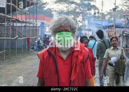 Ein heiliger, der eine Schutzmaske im Transit-Lagergelände von Gangsagar in Kalkata trägt. Gangasagar Messe ist die zweitgrößte Begräbnung der Hindu-Pilger nach Kumbh mela. Die Gangasagar-Mela wird jährlich auf der Insel Sagar beobachtet.jedes Jahr während Makar Sankranti besuchen eifrige Anhänger aus dem ganzen Land die insel sagar, um ein heiliges Bad im Zusammenfluss von Ganges und der Bucht von Bengalen zu nehmen und dann am Kapil Muni Ashram auf der Insel anzubeten. Der Tempel wird unter den Anhängern hoch verehrt.Dieses Jahr wird die Messe eingeschränkt und unter strengen COVID-Protokollen der Regierung wird die übliche Menge woul Stockfoto