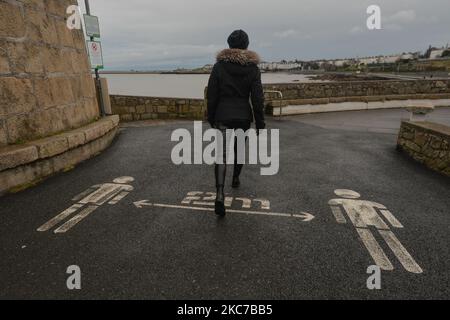 Eine Frau kommt an einem sozialen Distanzierungsschild 2m in der Nähe des Strandes von Seapoint in Dublin vorbei, während die Covid-19-Sperre auf Level 5 abgeschlossen wird. Irland hat die höchste Covid-19-Infektionsrate der Welt, nachdem in der vergangenen Woche mehr als 45.700 Fälle im Bundesstaat verzeichnet wurden. Heute Abend meldete das Gesundheitsministerium 4.929 neue Covid-19-Fälle und 8 Todesfälle für die Republik Irland. Eine Rekordzahl von 1.582 Covid-19 Patienten war im Krankenhaus. Die Zahl der Intensivpflegebedürftigen ist um 21 auf 146 Personen höher. Am Montag, den 11. Januar 2021, in Dublin, Irland. (Foto von Artur Widak/NurPhoto) Stockfoto