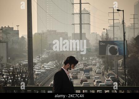 Ein iranischer Mann mit einer schützenden Gesichtsmaske geht während einer verschmutzten Luft nach dem Ausbruch der COVID-19 im Iran am 12. Januar 2021 entlang einer Straße im Norden Teherans. Teheran ist zwischen den Bergen eingekeilt und schmutzige Luft kann gefangen werden, wenn es keinen Wind oder Regen gibt. Iranische Gesundheitsexperten sagen, dass Tausende von Todesfällen pro Jahr durch Herzinfarkte und Atemwegserkrankungen verursacht werden, die durch Smog verursacht werden. (Foto von Morteza Nikoubazl/NurPhoto) Stockfoto