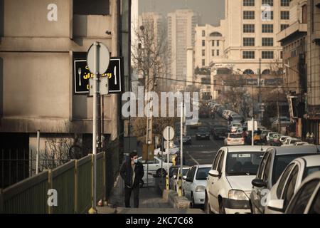 Ein iranischer Mann mit einer schützenden Gesichtsmaske geht während einer verschmutzten Luft nach dem Ausbruch der COVID-19 im Iran am 12. Januar 2021 entlang einer Straße im Norden Teherans. Teheran ist zwischen den Bergen eingekeilt und schmutzige Luft kann gefangen werden, wenn es keinen Wind oder Regen gibt. Iranische Gesundheitsexperten sagen, dass Tausende von Todesfällen pro Jahr durch Herzinfarkte und Atemwegserkrankungen verursacht werden, die durch Smog verursacht werden. (Foto von Morteza Nikoubazl/NurPhoto) Stockfoto