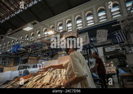 Eine Frau, die einen Gesichtsschutz trägt, wählt und bezahlt für ihre Meeresfrüchte. Tägliches Leben am 11. Oktober auf dem zentralen Fischmarkt von Varvakios in der Innenstadt Athens. Menschen werden als Schutzmaßnahme gegen die Ausbreitung der Coronavirus-Pandemie Covid-19 gesehen, da sie auf dem zentralen Markt einkaufen. Griechenland ist seit dem 7. November 2020 gesperrt. Athen, Griechenland am 2020. Oktober (Foto: Nicolas Economou/NurPhoto) Stockfoto