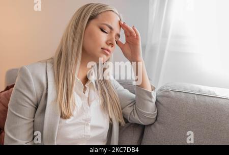 Porträt einer müden jungen Frau, die an Kopfschmerzen leidet Stockfoto
