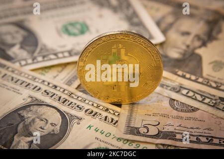 Bitcoin goldene physische Münze Illustration auf US-Dollar-Banknoten. Visuelle Darstellungen der digitalen Kryptowährung Bitcoin mit dem USD-Schein. Bitcoin mit dem Symbol BTC ist XBT eine beliebte digitale Währung, die Wachstum zeigte und weit verbreitet ist und von Banken, Märkten und anderen Dienstleistungen und Geschäften als Zahlungsmittel akzeptiert wird. Der heutige Wechselkurs für 1 Bitcoin Blockchain beträgt 34,588 US-Dollar. Am 7. Januar 2021 kreuzte der Bitcoin-Preis zum ersten Mal 40.000 und am nächsten Tag, am 8. Januar 2021, wurde Bitcoin mit dem historischen Rekordpreis von bis zu $41.973 gehandelt, während am nächsten Tag Stockfoto