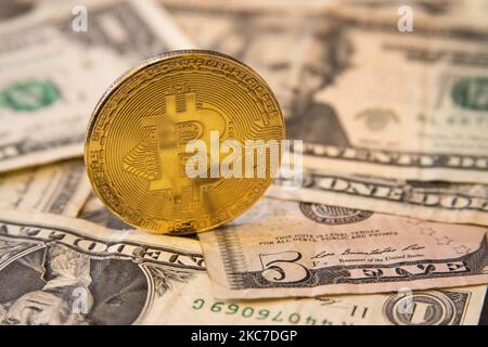 Bitcoin goldene physische Münze Illustration auf US-Dollar-Banknoten. Visuelle Darstellungen der digitalen Kryptowährung Bitcoin mit dem USD-Schein. Bitcoin mit dem Symbol BTC ist XBT eine beliebte digitale Währung, die Wachstum zeigte und weit verbreitet ist und von Banken, Märkten und anderen Dienstleistungen und Geschäften als Zahlungsmittel akzeptiert wird. Der heutige Wechselkurs für 1 Bitcoin Blockchain beträgt 34,588 US-Dollar. Am 7. Januar 2021 kreuzte der Bitcoin-Preis zum ersten Mal 40.000 und am nächsten Tag, am 8. Januar 2021, wurde Bitcoin mit dem historischen Rekordpreis von bis zu $41.973 gehandelt, während am nächsten Tag Stockfoto