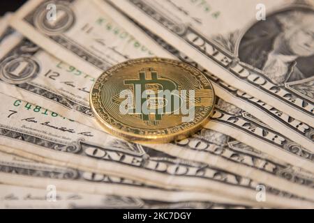 Bitcoin goldene physische Münze Illustration auf US-Dollar-Banknoten. Visuelle Darstellungen der digitalen Kryptowährung Bitcoin mit dem USD-Schein. Bitcoin mit dem Symbol BTC ist XBT eine beliebte digitale Währung, die Wachstum zeigte und weit verbreitet ist und von Banken, Märkten und anderen Dienstleistungen und Geschäften als Zahlungsmittel akzeptiert wird. Der heutige Wechselkurs für 1 Bitcoin Blockchain beträgt 34,588 US-Dollar. Am 7. Januar 2021 kreuzte der Bitcoin-Preis zum ersten Mal 40.000 und am nächsten Tag, am 8. Januar 2021, wurde Bitcoin mit dem historischen Rekordpreis von bis zu $41.973 gehandelt, während am nächsten Tag Stockfoto