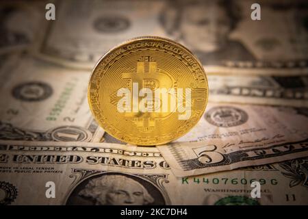 Bitcoin goldene physische Münze Illustration auf US-Dollar-Banknoten. Visuelle Darstellungen der digitalen Kryptowährung Bitcoin mit dem USD-Schein. Bitcoin mit dem Symbol BTC ist XBT eine beliebte digitale Währung, die Wachstum zeigte und weit verbreitet ist und von Banken, Märkten und anderen Dienstleistungen und Geschäften als Zahlungsmittel akzeptiert wird. Der heutige Wechselkurs für 1 Bitcoin Blockchain beträgt 34,588 US-Dollar. Am 7. Januar 2021 kreuzte der Bitcoin-Preis zum ersten Mal 40.000 und am nächsten Tag, am 8. Januar 2021, wurde Bitcoin mit dem historischen Rekordpreis von bis zu $41.973 gehandelt, während am nächsten Tag Stockfoto