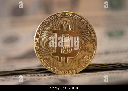 Bitcoin goldene physische Münze Illustration auf US-Dollar-Banknoten. Visuelle Darstellungen der digitalen Kryptowährung Bitcoin mit dem USD-Schein. Bitcoin mit dem Symbol BTC ist XBT eine beliebte digitale Währung, die Wachstum zeigte und weit verbreitet ist und von Banken, Märkten und anderen Dienstleistungen und Geschäften als Zahlungsmittel akzeptiert wird. Der heutige Wechselkurs für 1 Bitcoin Blockchain beträgt 34,588 US-Dollar. Am 7. Januar 2021 kreuzte der Bitcoin-Preis zum ersten Mal 40.000 und am nächsten Tag, am 8. Januar 2021, wurde Bitcoin mit dem historischen Rekordpreis von bis zu $41.973 gehandelt, während am nächsten Tag Stockfoto