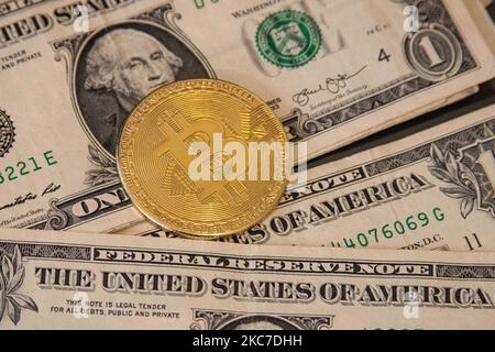 Bitcoin goldene physische Münze Illustration auf US-Dollar-Banknoten. Visuelle Darstellungen der digitalen Kryptowährung Bitcoin mit dem USD-Schein. Bitcoin mit dem Symbol BTC ist XBT eine beliebte digitale Währung, die Wachstum zeigte und weit verbreitet ist und von Banken, Märkten und anderen Dienstleistungen und Geschäften als Zahlungsmittel akzeptiert wird. Der heutige Wechselkurs für 1 Bitcoin Blockchain beträgt 34,588 US-Dollar. Am 7. Januar 2021 kreuzte der Bitcoin-Preis zum ersten Mal 40.000 und am nächsten Tag, am 8. Januar 2021, wurde Bitcoin mit dem historischen Rekordpreis von bis zu $41.973 gehandelt, während am nächsten Tag Stockfoto