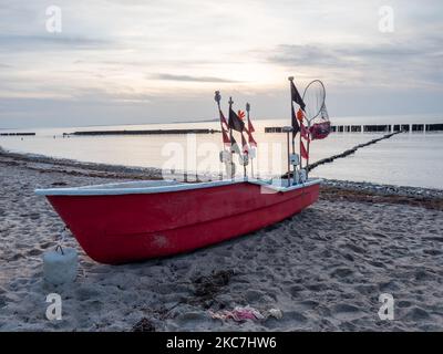 Rotes Fischerboot liegt am Strand der Insel Rügen im Dorf Dranske. Abends windstill am ostseeufer Stockfoto