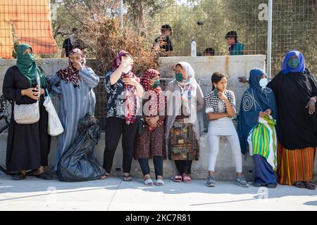 Frauen mit Gesichtsmasken warten getrennt von Männern auf Nahrung. Humanitäre Hilfe wird von der NGO Team Humanity Denmark an Asylsuchende geleistet, nachdem die Flüchtlinge und Migranten ihre Körpertemperatur getestet haben, um zu verhindern, dass Menschen in die Einrichtung mit der Möglichkeit der Ausbreitung der Pandemie, dem Covid-19 Coronavirus, einreisen. Die Anlage befindet sich in der Nähe des ehemaligen Moria-Hotspot-Camps. Mehr als 10,000 Asylsuchende sind obdachlos und hilflos, was dazu führt, dass sie am Straßenrand schlafen und leben und nach dem Brand in Moria Refugee C keine Unterkunft, Nahrung, Wasserversorgung, Einrichtung, Infrastruktur oder Hilfe haben Stockfoto