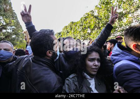 Ein junger Protestler macht ein Siegeszeichen, als seine commodores mit Mitgliedern der Sicherheitskräfte (nicht gezeigt) während einer regierungsfeindlichen Demonstration, die am 19. Januar 2021 in der tunesischen Hauptstadt Tunis auf der Avenue Habib Bourguiba stattfand, gegen die Regierung des Premierministers Hichem Mechichi protestieren, Und zur Unterstützung der Protestbewegungen, die Tunesien in mehreren Städten über Nacht in den vergangenen Tagen getroffen haben. Demonstranten prallten mit den Sicherheitskräften zusammen, die Tränengas abfeuerten und Pfefferspray verwendeten, um sie zu zerstreuen. Sie behaupteten auch, dass Jugendliche, die während der Haft von der Polizei verhaftet wurden, freigelassen wurden Stockfoto