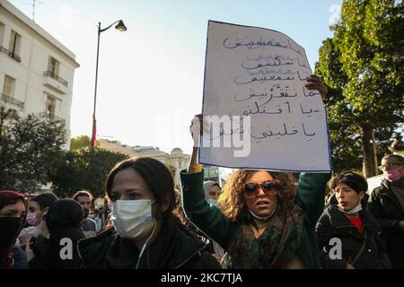 Eine junge Protesterin hebt ein Plakat auf, auf dem auf Arabisch steht: ‘Verarmung mich nicht, schweige mich nicht, unterdrücke mich nicht, marginalisiere mich nicht, Entweder Sie töten mich oder Sie lassen mich leben“, als sie an einer Anti-Regierungsdemonstration in der Avenue Habib Bourguiba in der Hauptstadt Tunis, Tunesien, am 19. Januar 2021 teilnahm, um gegen die Regierung des Premierministers Hichem Mechichi zu protestieren, Und zur Unterstützung der Protestbewegungen, die Tunesien in mehreren Städten über Nacht in den vergangenen Tagen getroffen haben. Die Demonstranten kollidierten mit den Sicherheitskräften, die Tränengas abfeuerten und Pfefferspray verwendeten, um zu versuchen Stockfoto