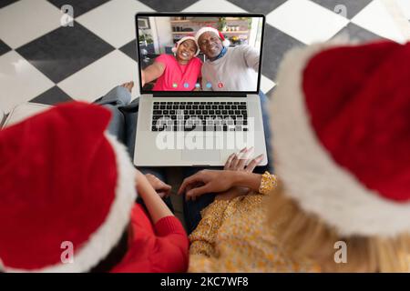 Kaukasische Mutter und Tochter, die ein weihnachtliches Videogespräch mit einem älteren afroamerikanischen Paar führen Stockfoto