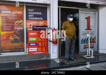 An einer Tankstelle in Kalkutta steht ein Mann mit Maske neben einer Tafel, auf der neue Preise für verschiedene Brennstoffe angezeigt werden. Die Benzinpreise in Kalkutta erreichen nach dem Anstieg der Rohölpreise im Land einen neuen Höhepunkt (Foto: Debarchan Chatterjee/NurPhoto) Stockfoto